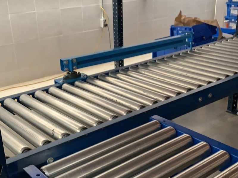 Detalle de transportador de rodillos de acero para manejo de cajas