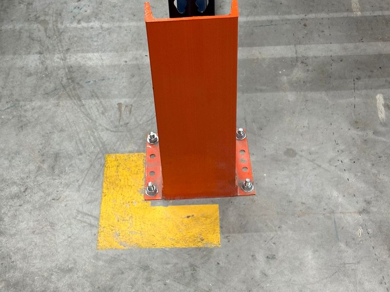 Protector de poste de acero anclado en la base de un rack industrial