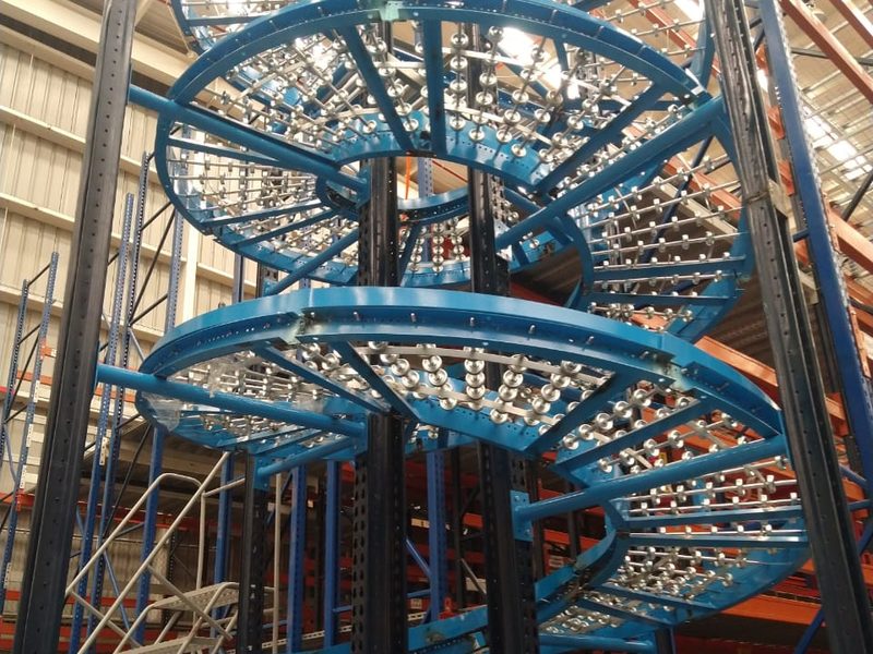 Tobogán espiral de gravedad instalado por Racks Solutions México para descenso de mercancía entre niveles